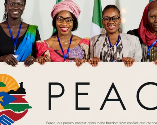 Group of women holding a sign that reads PEACE, representing SSDAA's peacebuilding initiatives